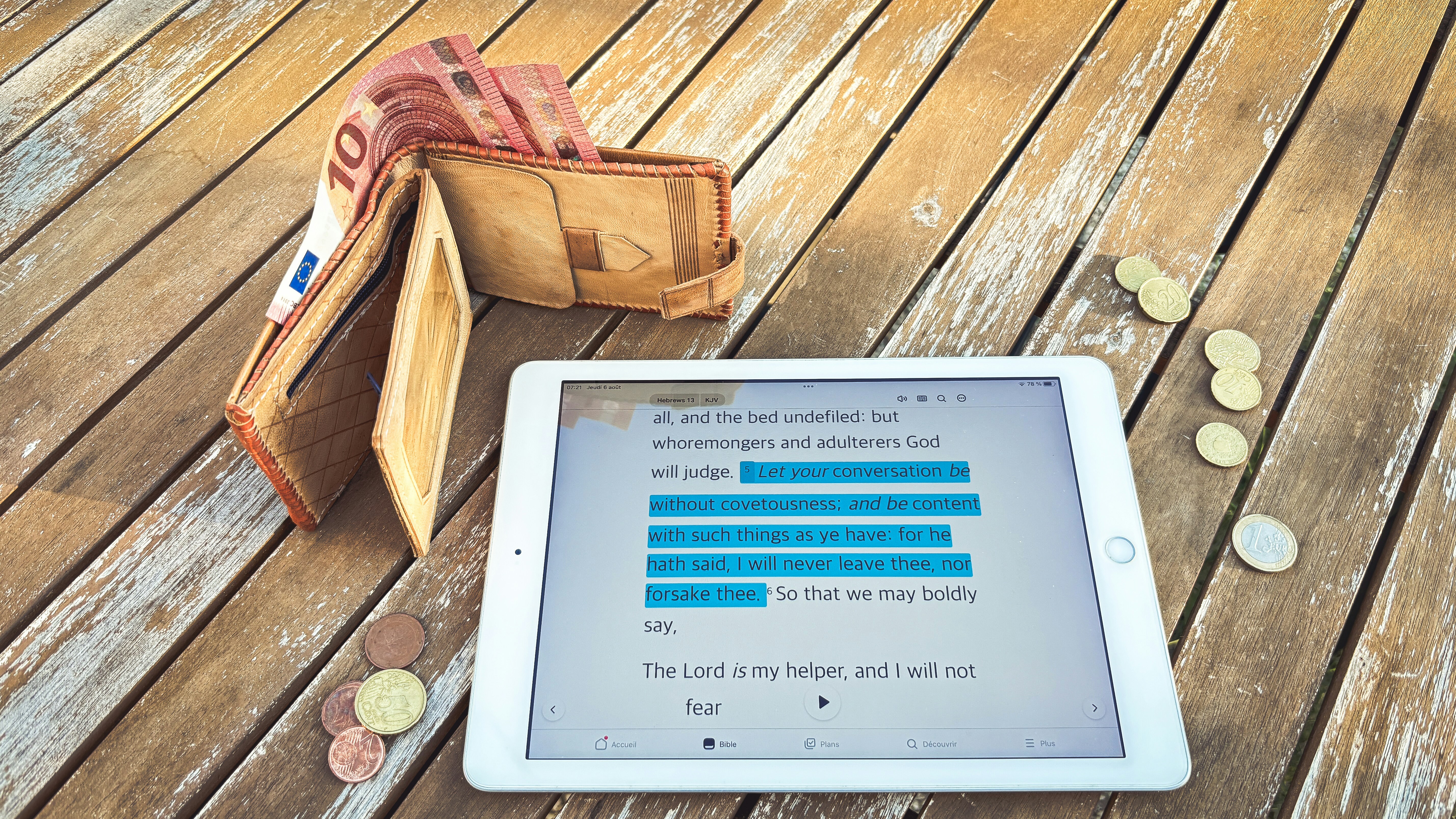 Wallet, tablet with financial data, and coins on wooden table